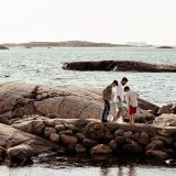 Pappa och söner på klipphällar vid havet håller fiskehåvar