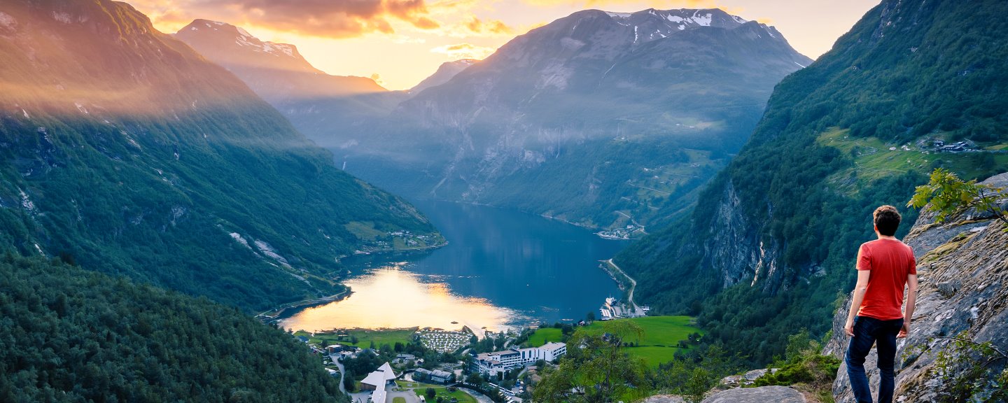 Man som beundrar Geiranger och Geirangerfjorden vid solnedgången, Norge